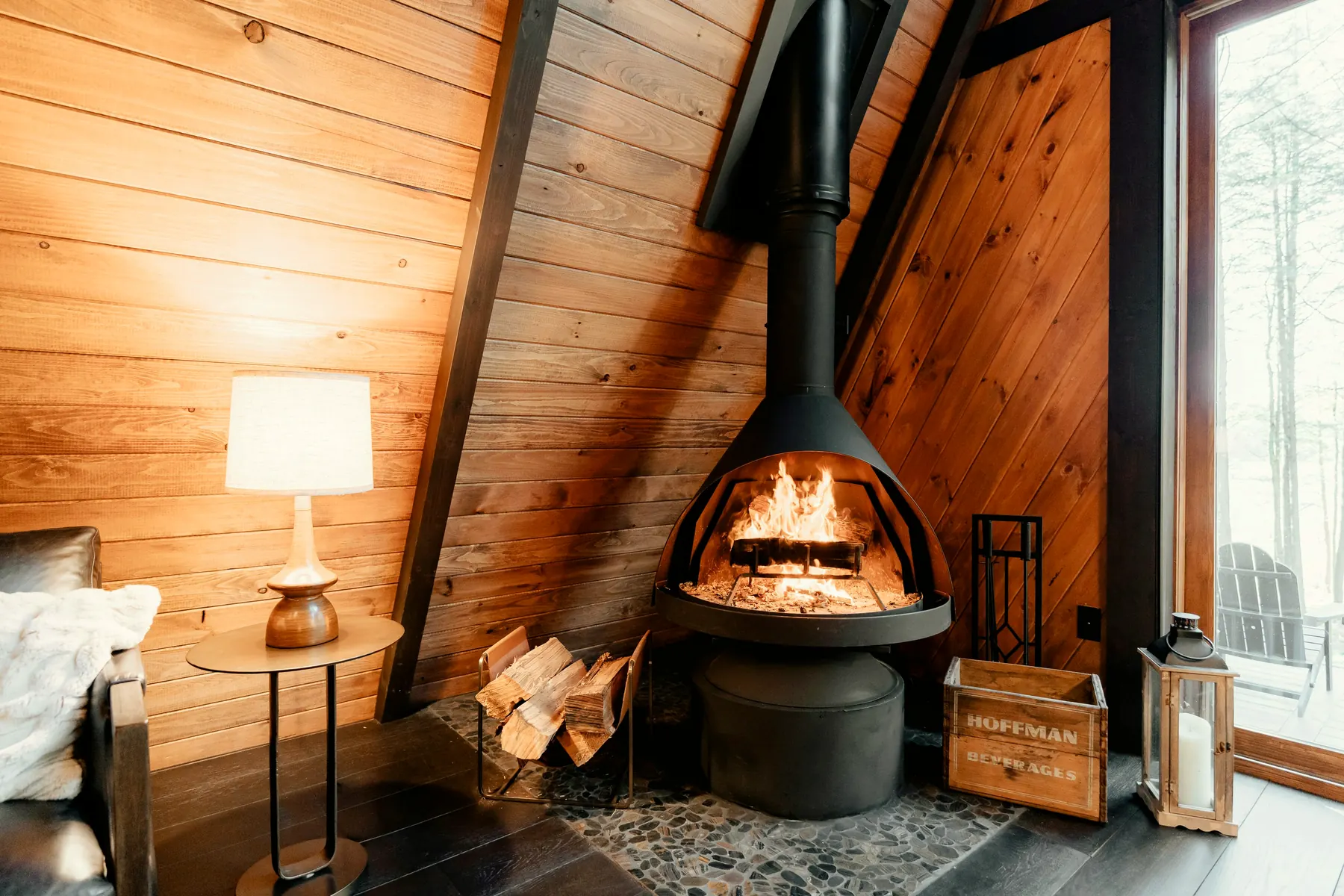 Gemütliches Chalet-Wohnzimmer mit brennendem Holzofen und Lampenlicht